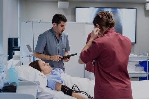 Un estduiante del área de salud realiza sus prácticas con una paciente de la mano de su profesora en el centro de Simulación de UNIE, que es un entorno seguro y realista para trabajar en casos clínicos, practicar las habilidades.