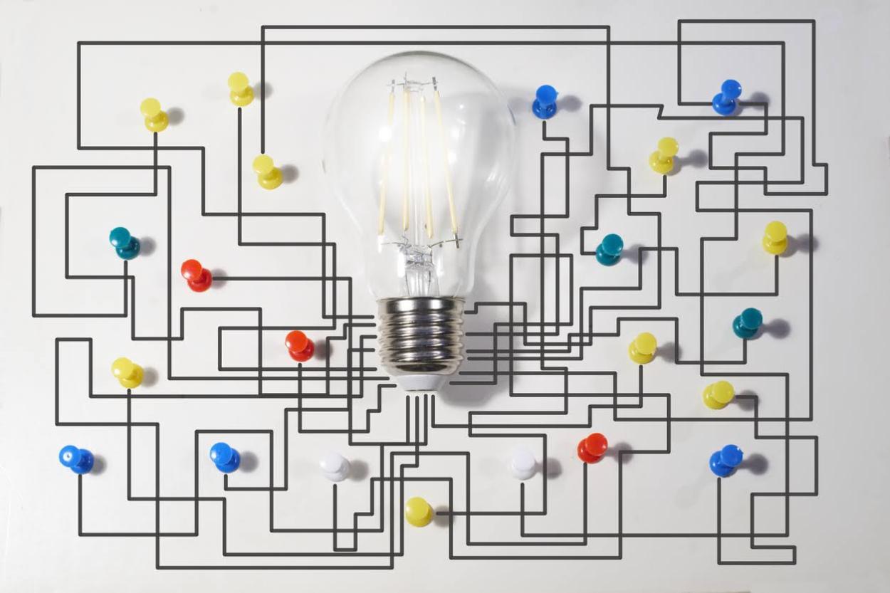 Bombilla con una pared de fondo y un mapa de chinchetas