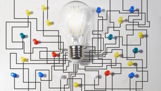 Bombilla con una pared de fondo y un mapa de chinchetas