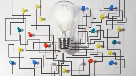 Bombilla con una pared de fondo y un mapa de chinchetas