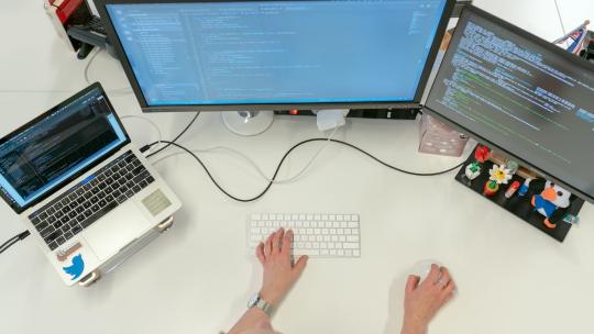 Persona trabajando con varias pantallas en su escritorio.