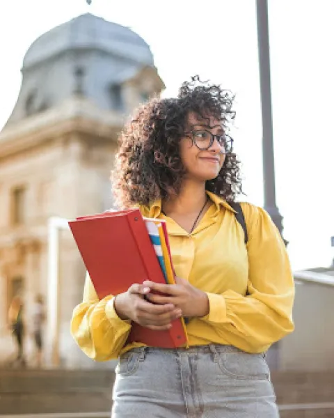 Chica posando con una libreta en la mano.