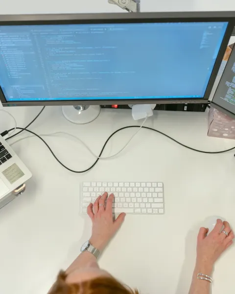 Persona trabajando con varias pantallas en su escritorio.